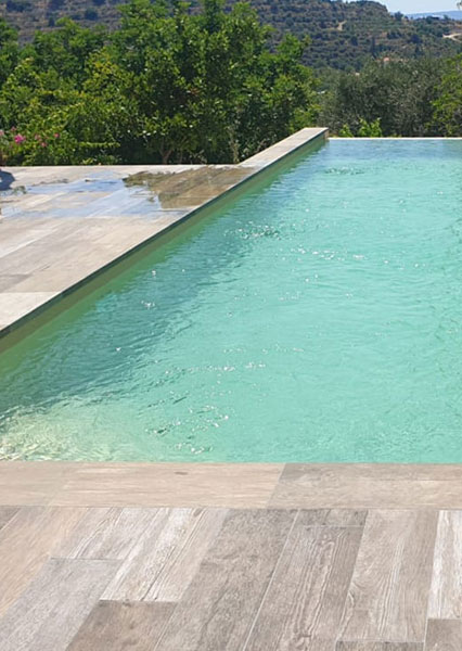 Coronación para la piscina en tonos madera grises de varias tonalidades y antideslizante.
